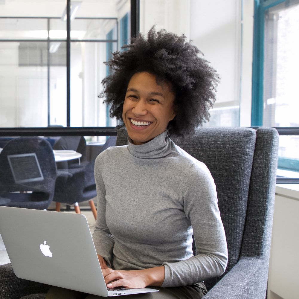 Pessoa inteligente sorrindo para a câmera com um laptop no colo