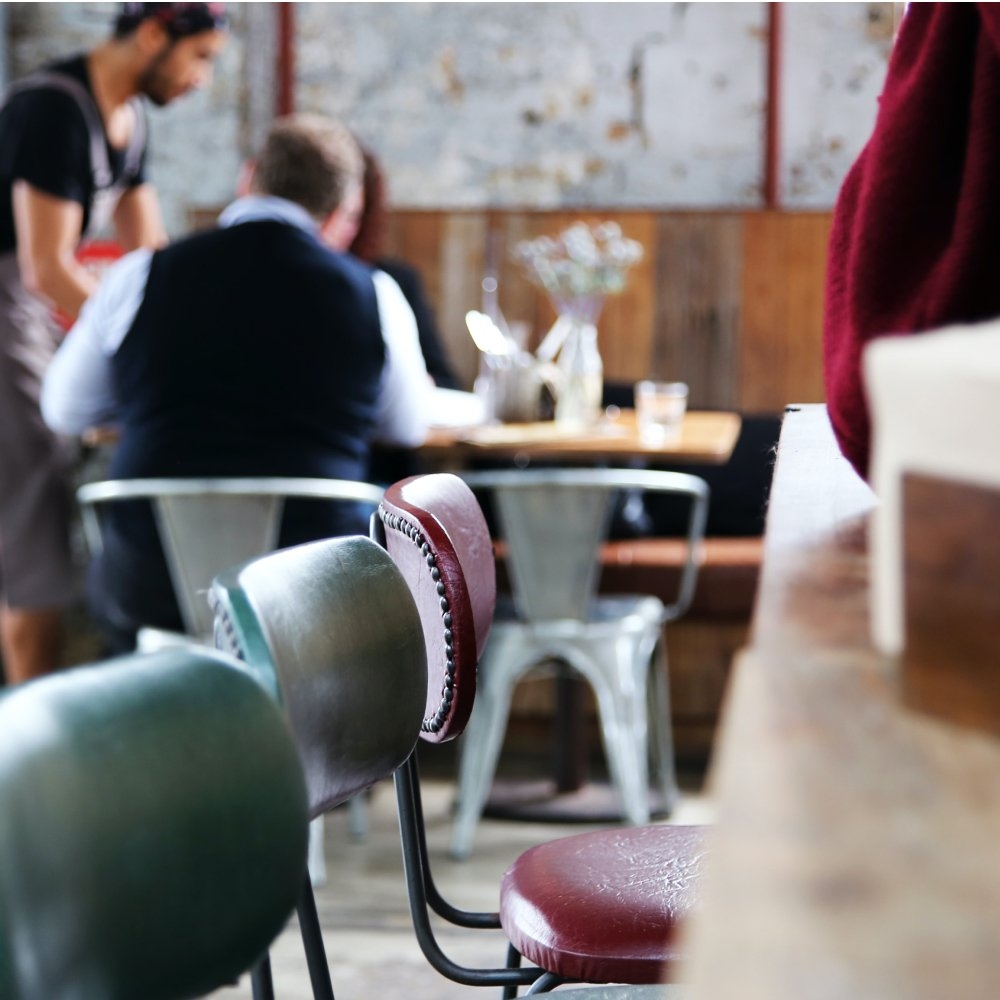 hotel restaurant in the background with focus on 3 vintage-looking chairs pulled up to a table in the foreground