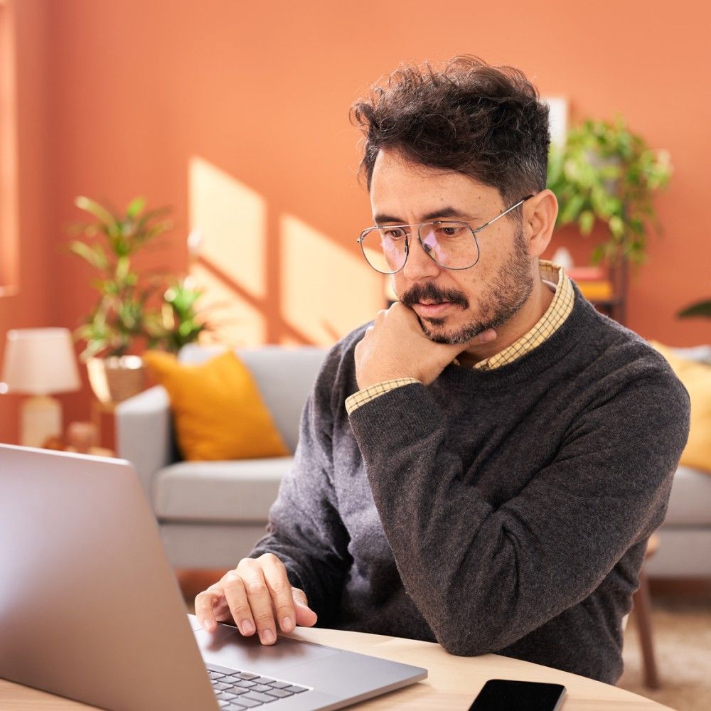 Homem olhando atentamente para a tela de um laptop