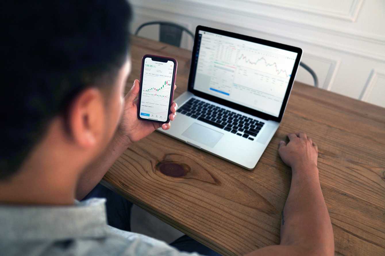 Man looking at his finances on his mobile and
laptop