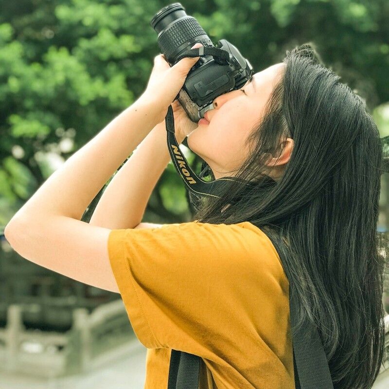 Femme portant un appareil photo à son œil et le pointant vers le ciel